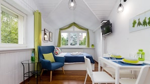 A cozy room with a bed, a dining table set for two, a small table with a bottle, and a chair. - Mokotów Cosy House Studio (Warszawa)