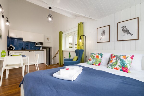 Une chambre d’hôtel moderne équipée d’un lit, d’un bureau et d’une kitchenette.