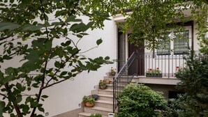 A residential building with a staircase leading to a balcony, surrounded by greenery and potted plants. - Mokotów Cosy House Studio (Warszawa)