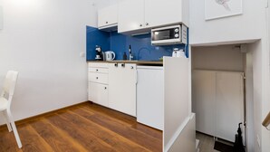 A compact kitchen with white cabinets, a microwave, and a blue backsplash. - Mokotów Cosy House Studio (Warszawa)