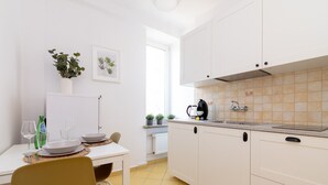 Une cuisine moderne avec des meubles blancs, un pare-feu en carreaux et un coin repas avec une table dressée pour deux personnes.