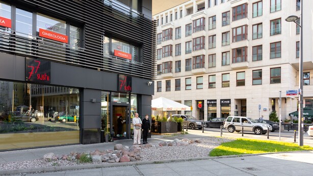 Un bâtiment moderne abritant un restaurant de sushis au rez-de-chaussée, une clinique médicale au deuxième étage et un espace de stationnement à l’avant.