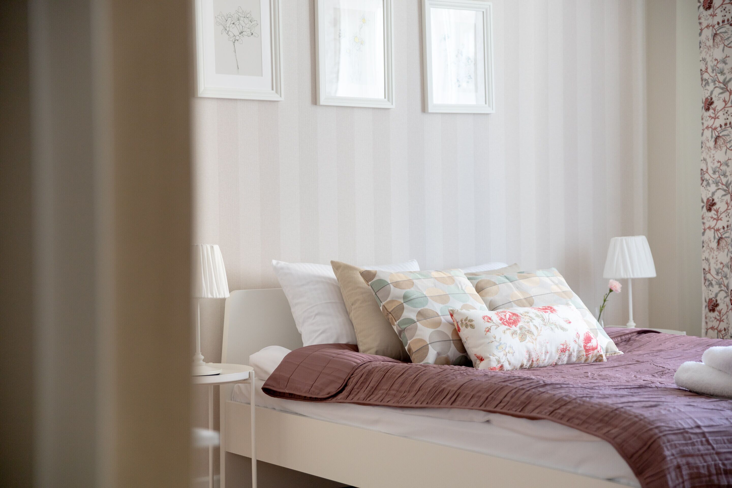 A neatly arranged bedroom with a bed, pillows, and bedside lamps.