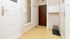 Un couloir avec une porte blanche, une porte en bois et un radiateur blanc.