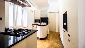 Una cocina moderna con una isla central, horno empotrado y campana extractora de acero inoxidable.