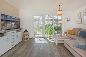 A modern living room with a sofa, coffee table, and a TV on a cabinet.