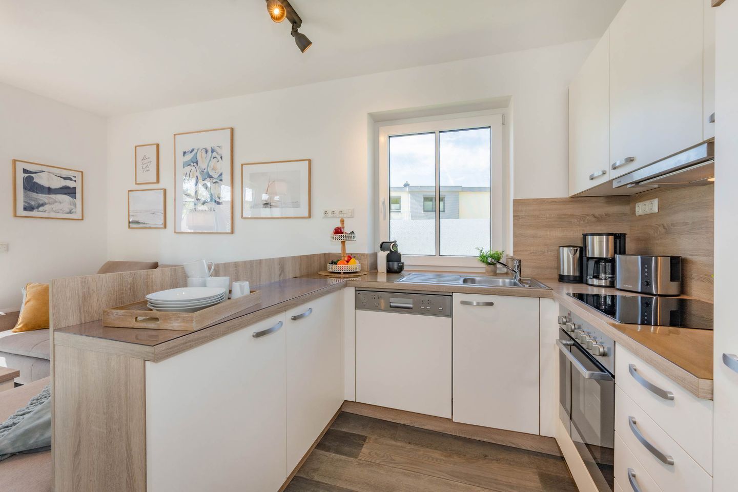 A modern kitchen with white cabinetry, a built-in oven, and a coffee machine.