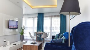 Uma sala de estar moderna com um sofá azul, uma mesa de centro e uma TV fixada na parede.