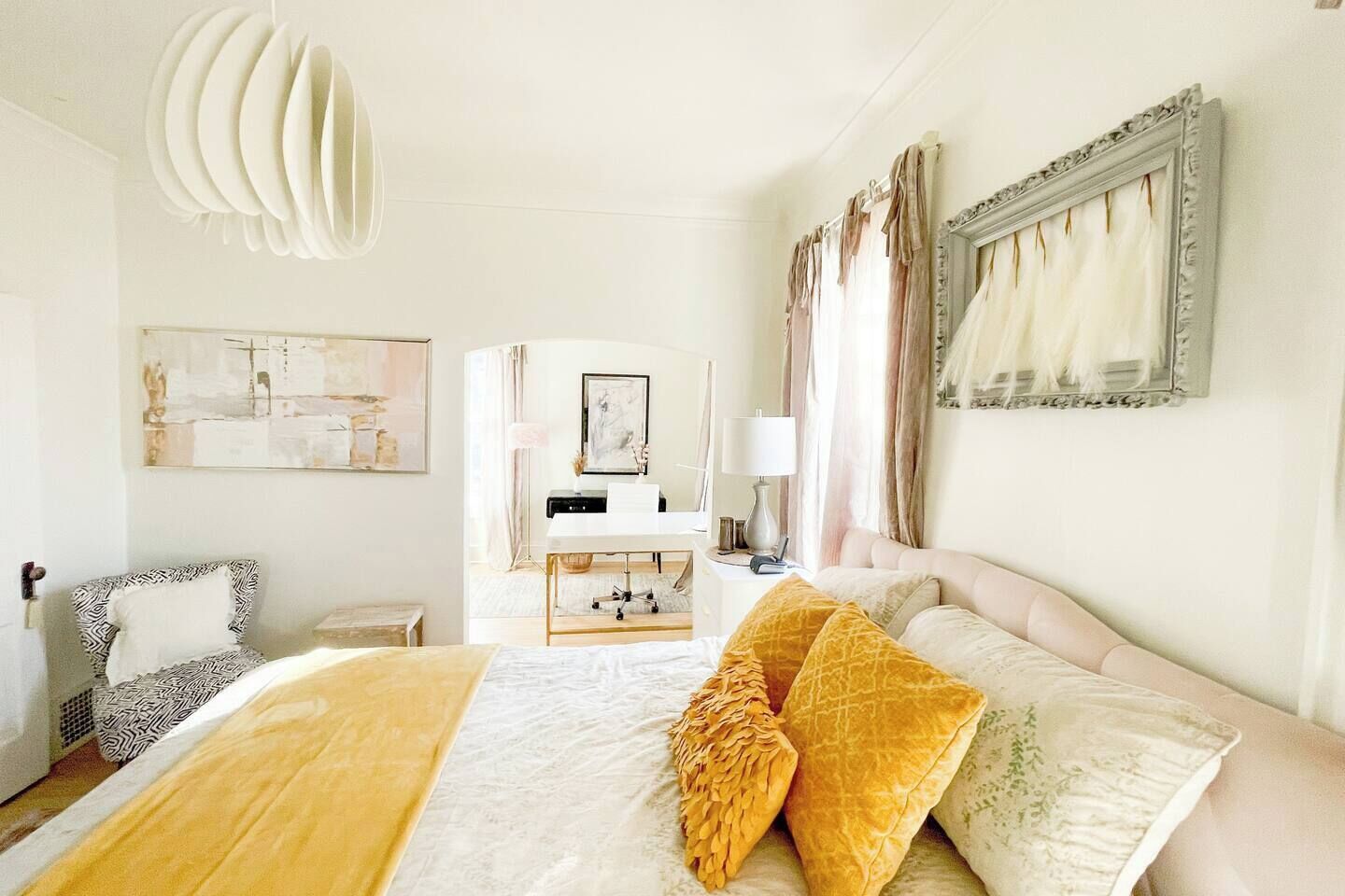 A hotel room with a large bed, a desk, a chair, and artwork on the walls.