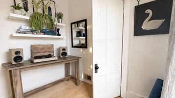 A room with a wooden console table, a white door, a wall-mounted mirror, and a framed swan picture.