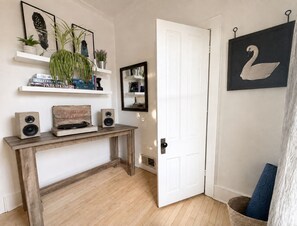 A room with a wooden console table, a white door, a wall-mounted mirror, and a framed swan picture. - Historic Downtown-Old World Charm-Dining-Coffee (Delafield)