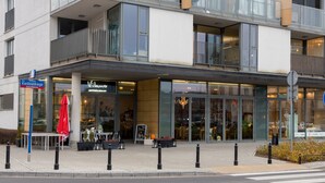Een modern gebouw met een restaurant genaamd "Vilano" en een bord met "Kleostwicego".