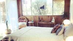 Una camera da letto con un letto grande, un comodino, una sedia e una finestra vista alberi.