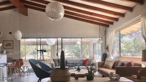 Un soggiorno spazioso con una grande finestra, una poltrona blu, un tavolino in legno e un cactus come elemento decorativo.