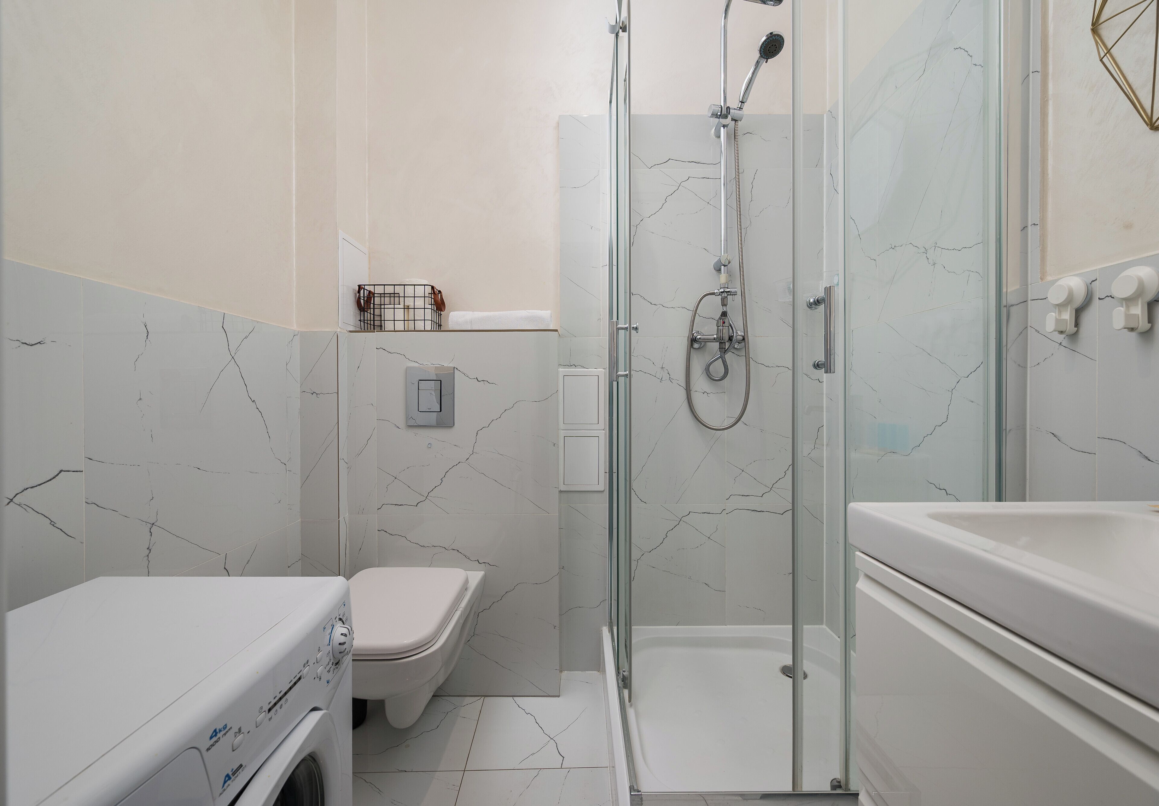 Un baño con ducha de vidrio, inodoro y lavadora.