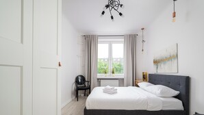 Een slaapkamer met een bed, een stoel, een raam en een schilderij aan de muur.
