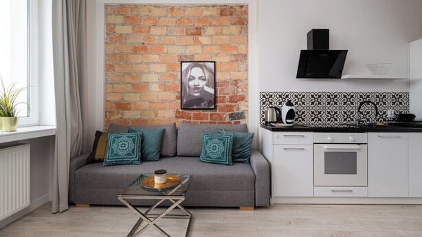 Een moderne woonkamer met een grijze bank, een salontafel en een bakstenen muur.