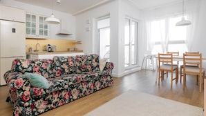 A modern living space with a floral sofa, wooden dining table, and chairs.