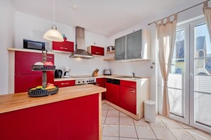 Una cocina moderna con armarios rojos, una isla central, una estufa y un microondas.