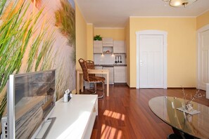 A modern kitchen with white cabinets, a dining area with a glass table, and a large painting on the wall.