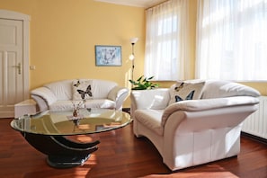 Ein Wohnzimmer mit zwei weißen Sofas, einem Glastisch und einem Gemälde an der Wand.