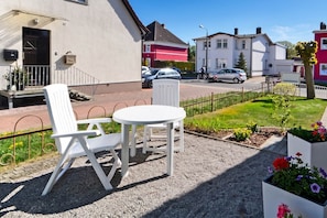 Eine Terrasse mit Gartenmöbeln, einem Kiesbelag und einem Blumenbeet.