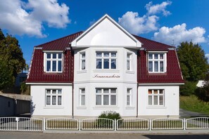 A two-story building with a white facade and red roof, labeled 'Sonneschein.'