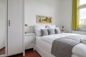 Ein Schlafzimmer mit einem Bett, Nachttischen, einem Gemälde und einem Fenster mit Vorhängen.