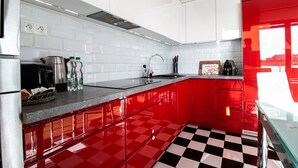 A kitchen with red and white cabinetry, a black and white checkered floor, and a stainless steel refrigerator.