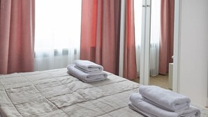 Una habitación de hotel con una cama, un espejo grande y cortinas rojas.