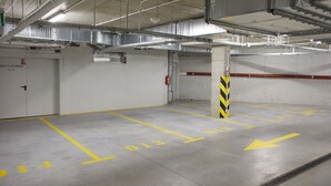 Eine Parkgarage mit Betonböden, ausgewiesenen Parkfeldern und Lüftungskanälen.