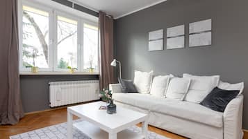 Un salon moderne avec un canapé blanc, une table basse blanche et une fenêtre avec des rideaux.