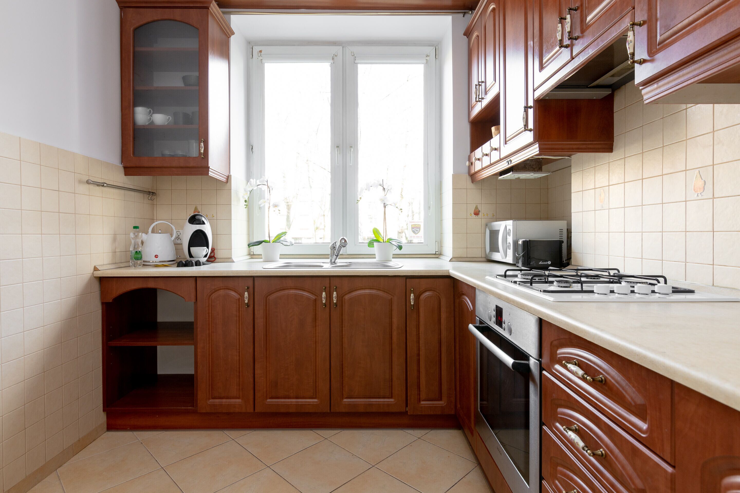 Une cuisine avec des meubles de rangement en bois, une cuisinière à gaz, un four à micro-ondes et un évier.