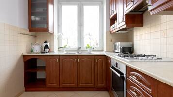 Une cuisine avec des meubles de rangement en bois, une cuisinière à gaz, un four à micro-ondes et un évier.