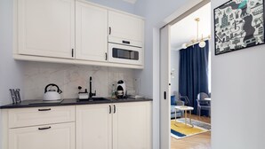 Een moderne keuken met witte kastjes, een magnetron en een waterkoker op het aanrecht.