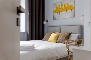 Een moderne hotelkamer met een opgemaakt bed, een stadsgezichtschilderij aan de muur, en een bureau met een stoel.