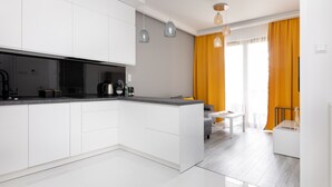 A modern kitchen with white cabinetry, a central island, and pendant lighting. - Wilanów Gardens with Balcony (Warszawa)