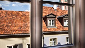A window with a view of a building with a red-tiled roof and a clock tower. - Świętojsańska  Old Town  Apartment (Warszawa)