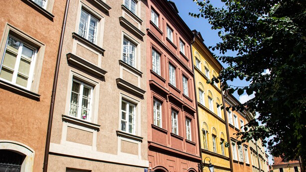 A row of multi-story buildings with large windows and a street in between. - Świętojsańska  Old Town  Apartment (Warszawa)