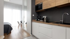 Una cocina moderna con armarios de madera, un microondas negro y un lavamanos de acero inoxidable.