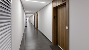 Un pasillo largo y estrecho con puertas de madera, cada una con un número.