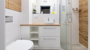 Un baño moderno con inodoro, lavamanos y cabina de ducha de vidrio.