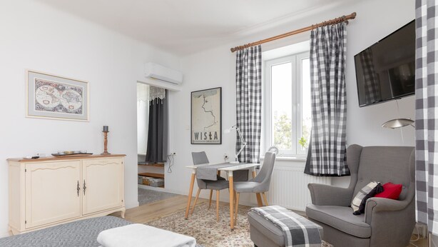 A modern bedroom with a bed, a grey armchair, a small table, and a TV.