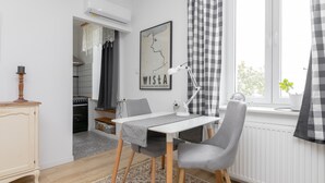 A modern kitchen with a white countertop, a stove, and a window with checkered curtains.