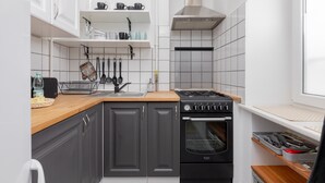 A compact kitchen with dark grey cabinets, a wooden countertop, a stove, and a built-in oven.