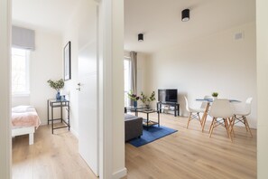 A modern living room with a sofa, coffee table, TV, and dining area with chairs. - Koszykowa Exquisite Apartment (Warszawa)