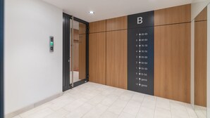 A modern elevator with a digital display, a wooden panel wall with a floor number indicator, and a clean, tiled floor. - Warsaw Spire Stylish Apartment (Warszawa)