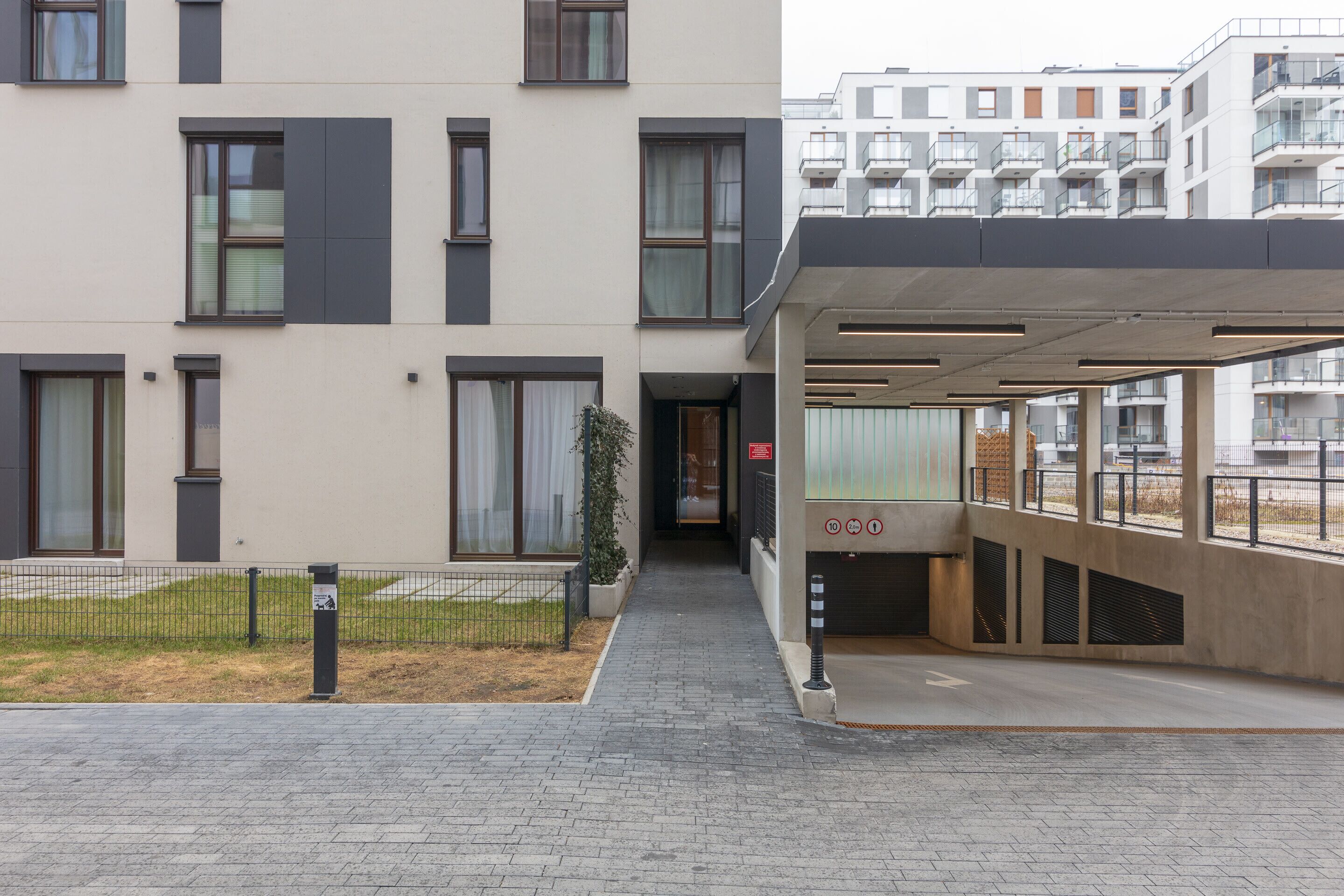 En modern byggnad med en inglasad entré, stora fönster och en stenlagd gångväg.