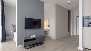 A modern living room with a flat-screen TV mounted on the wall, a grey entertainment unit, and a wooden floor. - Warsaw Spire Stylish Apartment (Warszawa)