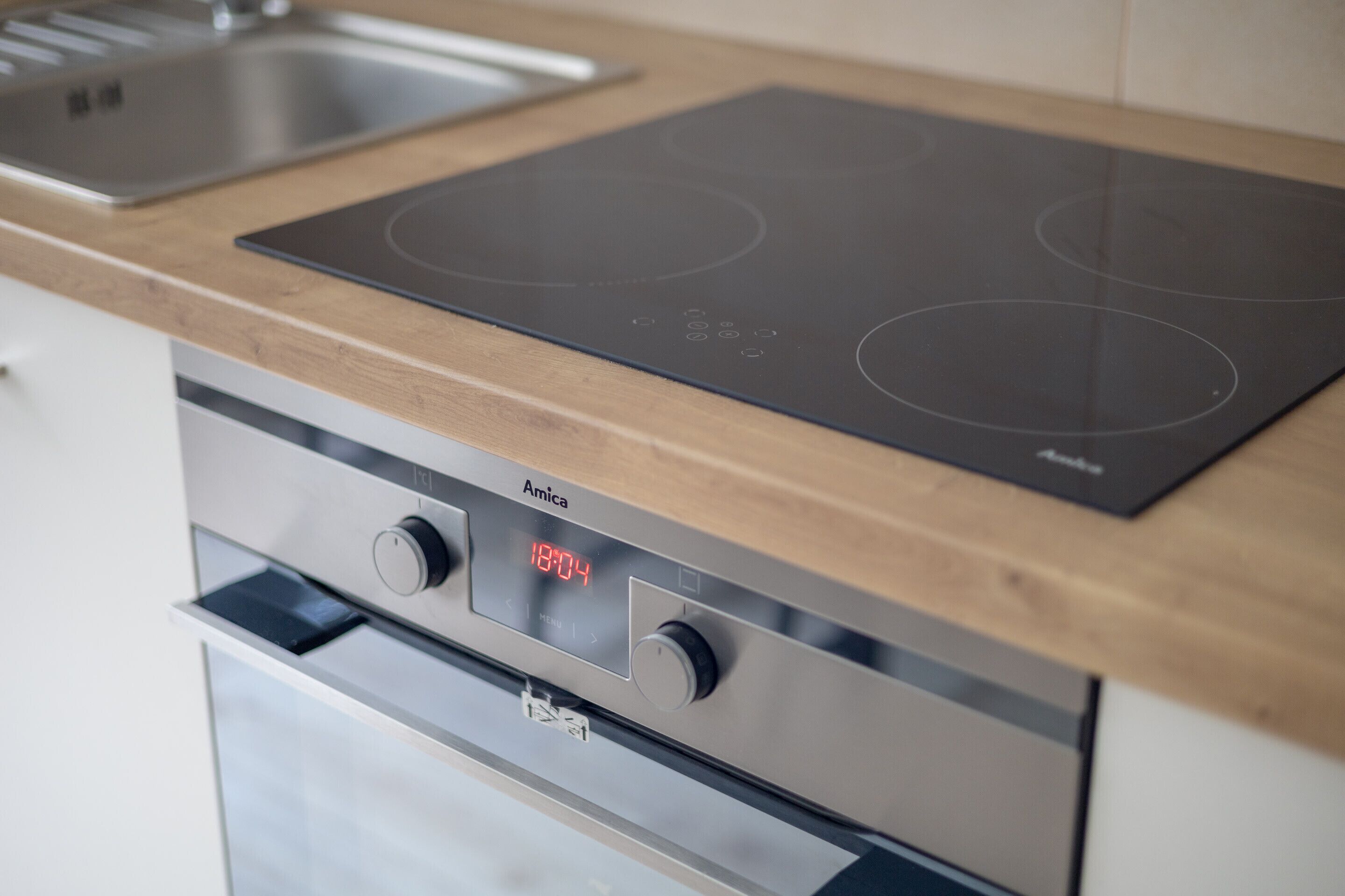 Une cuisine moderne dotée d’une plaque de cuisson à induction intégrée et d’un four en acier inoxydable.